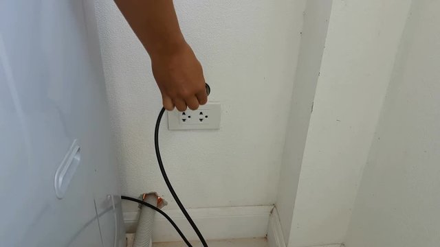 close-up man unplug electric washing machine after using, Thailand
