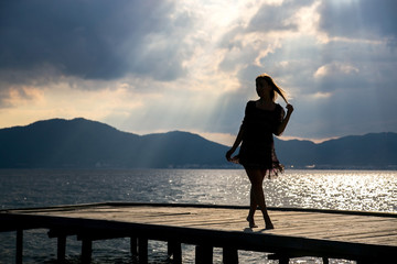 Fototapeta premium Girl at sunset on the pier