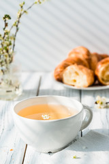 Cup of herbal tea and fresh croissants on plate