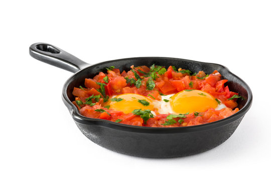 Shakshuka in iron frying pan isolated on white background. Typical food in Israel.

