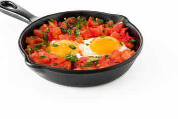 Shakshuka in iron frying pan isolated on white background. Typical food in Israel.

