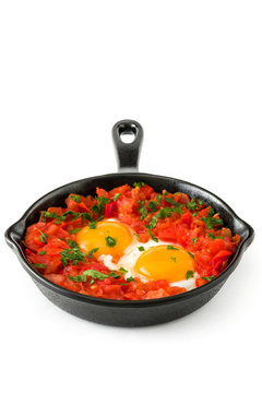 Shakshuka in iron frying pan isolated on white background. Typical food in Israel.

