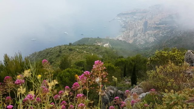 Aerial View of Mountain with Fog and Flowers. Principality of Monaco in the Background - 4K Video
