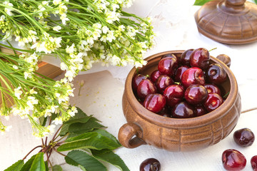 Berries of fresh cherry with cherry green leaves on an old white wooden background
