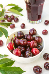 Berries of fresh cherry with cherry green leaves on an old white wooden background