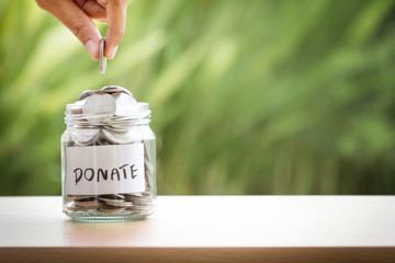 Hand putting Coins in glass jar for giving and donation concept - 158747798