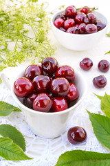 Berries of fresh cherry with cherry green leaves on an old white wooden background