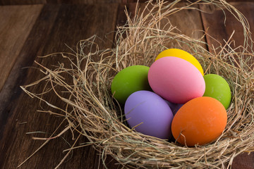 Easter eggs in nest on old wooden background