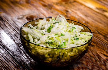Salad with the cabbage and green onion on wooden table
