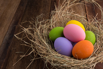 Easter eggs in nest on old wooden background