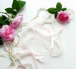 Beautiful pink roses, ornaments and lace on a white background. Top view. Flat lay. Copy space