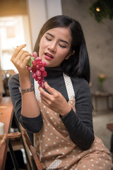 Pretty Asian woman eating an grape at restaurant 