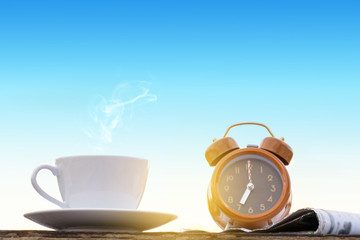 coffee cup clock and news paper on old wooden table
