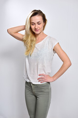 A girl holds her hand on the back of her neck and looks down