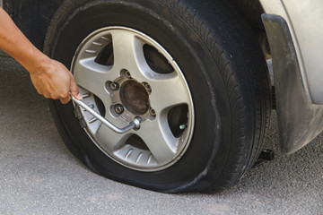 Changing tire with wheel wrench.