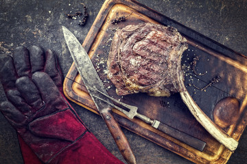 Barbecue Wagyu Tomahawk Steak as top view on burnt cutting board