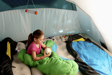 Fototapeta na wymiar Little caucasian girl (elementary age) in the tent watching terrestrial globe.