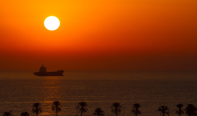 Sunset over the ocean with sun ball and ship