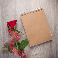 Red rose and note book on old wood background
