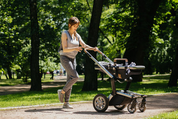Fototapeta na wymiar Series of exercises with a stroller - young gorgeous mother with baby stroller workout in the park. Sport, maternity, healthy lifestyle concept