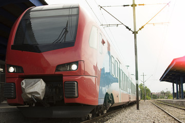 Naklejka premium Modern high-speed train on a clear day with motion blur. Beautiful railway station with modern red commuter train.