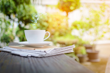 coffee cup clock and news paper on old wooden table nature background