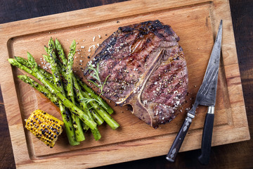 Barbecue dry aged Wagyu Porterhouse Steak with green Asparagus as close-up on a cutting board