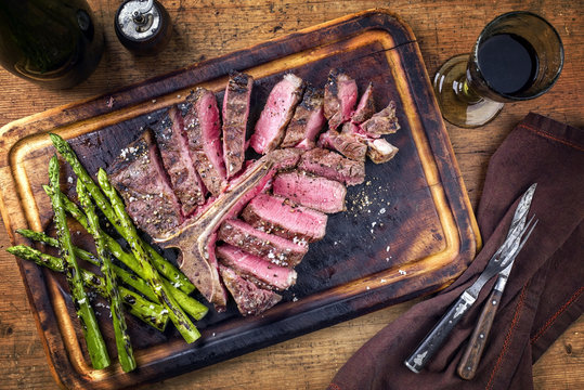 Barbecue dry aged Wagyu Porterhouse Steak sliced with green Asparagus on a cutting board