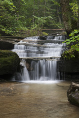 Beautiful waterfalls on golden rocks surrounded by moss on boulders.