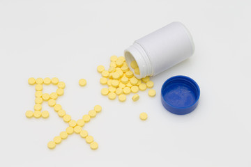 Yellow pills spill put of the bottle and arranged in the word RX Logo