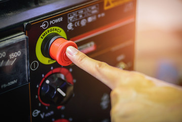 Finger push on red emergency stop switch welding machine in steel industry.