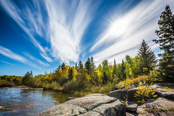 Incredible cirrus clouds  and huge flat stones in Old Pinawa Dam Park. Indian summer in Manitoba, Canada. The concept of ecological tourism