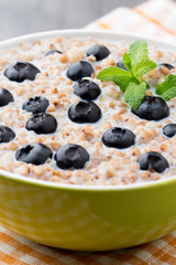 Buckwheat porridge in a bowl with mint leaves and blueberries.