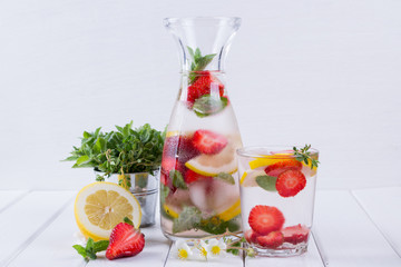 Mineral infused water with strawberry, ice, herb and mint leaves on white background, homemade detox soda water recipe.