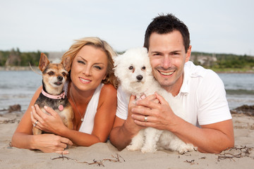 Happy couple on the beach with their two pet dogs