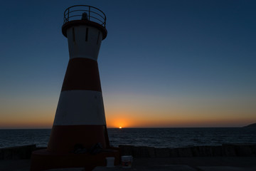 Lighthouse with the sunset at dusk on the beach © Gabriel