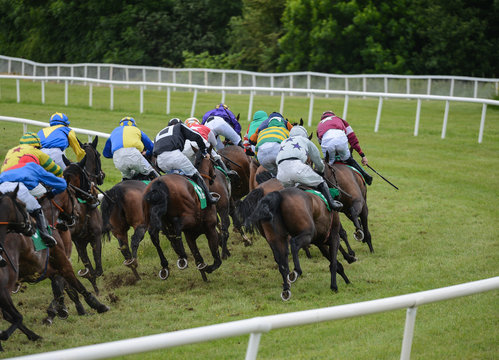 Competing race horses and jockeys galloping on the turn of the race track