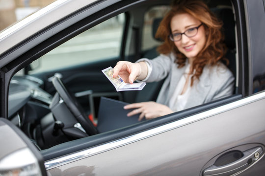 Woman sitting in car and showing driver license. Driving school concept.	