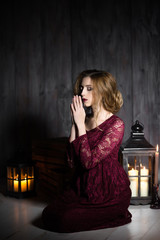 Fototapeta premium Humble young woman in a purple long dress praying to our lord Jesus Christ