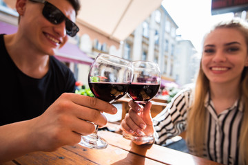 Young couple with glasses of red wine in a restaurant with city view