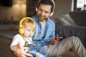 Obraz premium Father and son with smartphone and earphones, listening music.