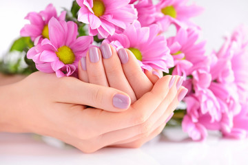 Hands of a woman with pink manicure on nails and pink flowers