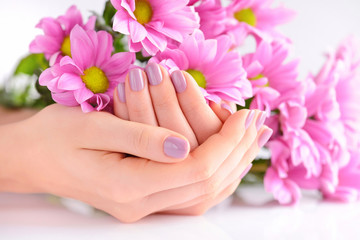 Obraz na płótnie Canvas Hands of a woman with pink manicure on nails and pink flowers
