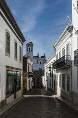Fototapeta na wymiar Europa, Portugalia, Algarve, miasto FARO - Tradycyjna wąska ulica. Wieczór, długie cienie. Na wprost dzwonnica. 