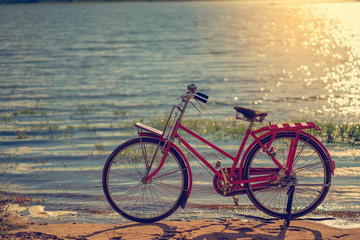 Fototapeta premium red bicycle beside the river with blue sky