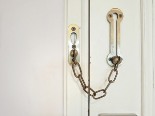 Door locked by door chain for safety room in hotel, closeup.
