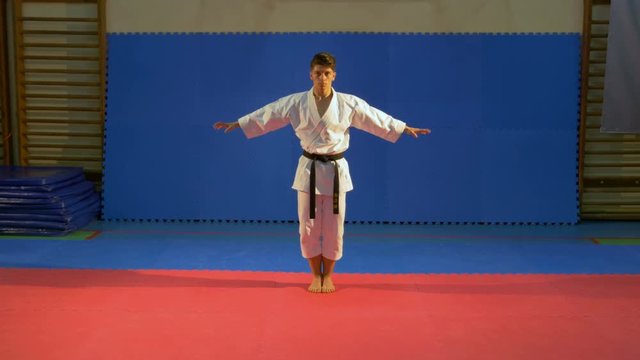 Teenager boy performs kata in sports hall during his karate training