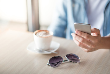 man hand texting message on social media application by phone, casual professional entrepreneur using smartphone in cafe or coffee shop, modern lifestyle and digital age concepts
