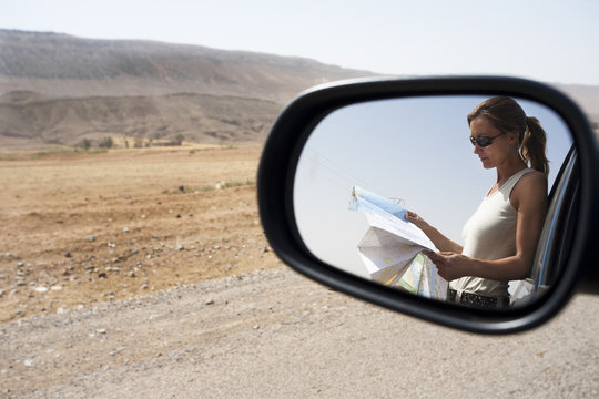 femme seule en voiture au milieu du désert qui cherche sa route sur une carte