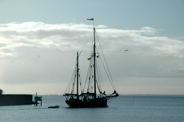 Silhouette of old sail ship leaving harbor. © Kim